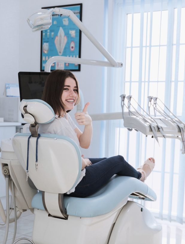 Smiling patient giving a thumbs up from the dental chair