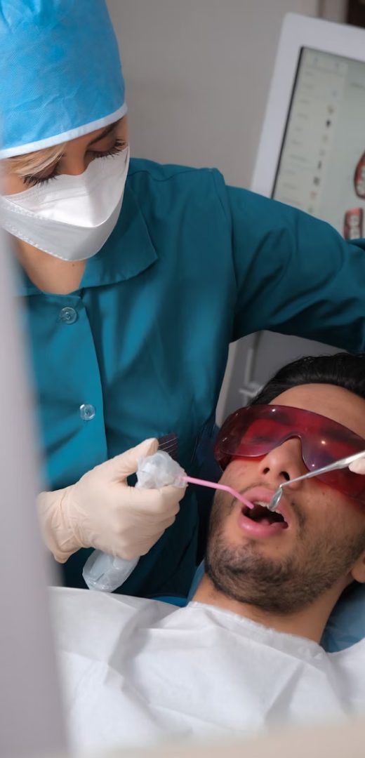 Patient wearing protective glasses while a dentist works on his teeth
